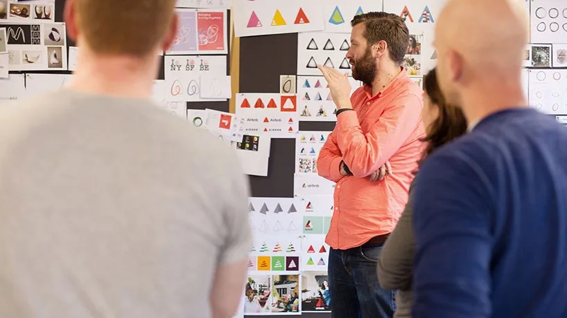 DesignStudio and Airbnb teams reviewing early logo sketches and mood boards on a studio wall
