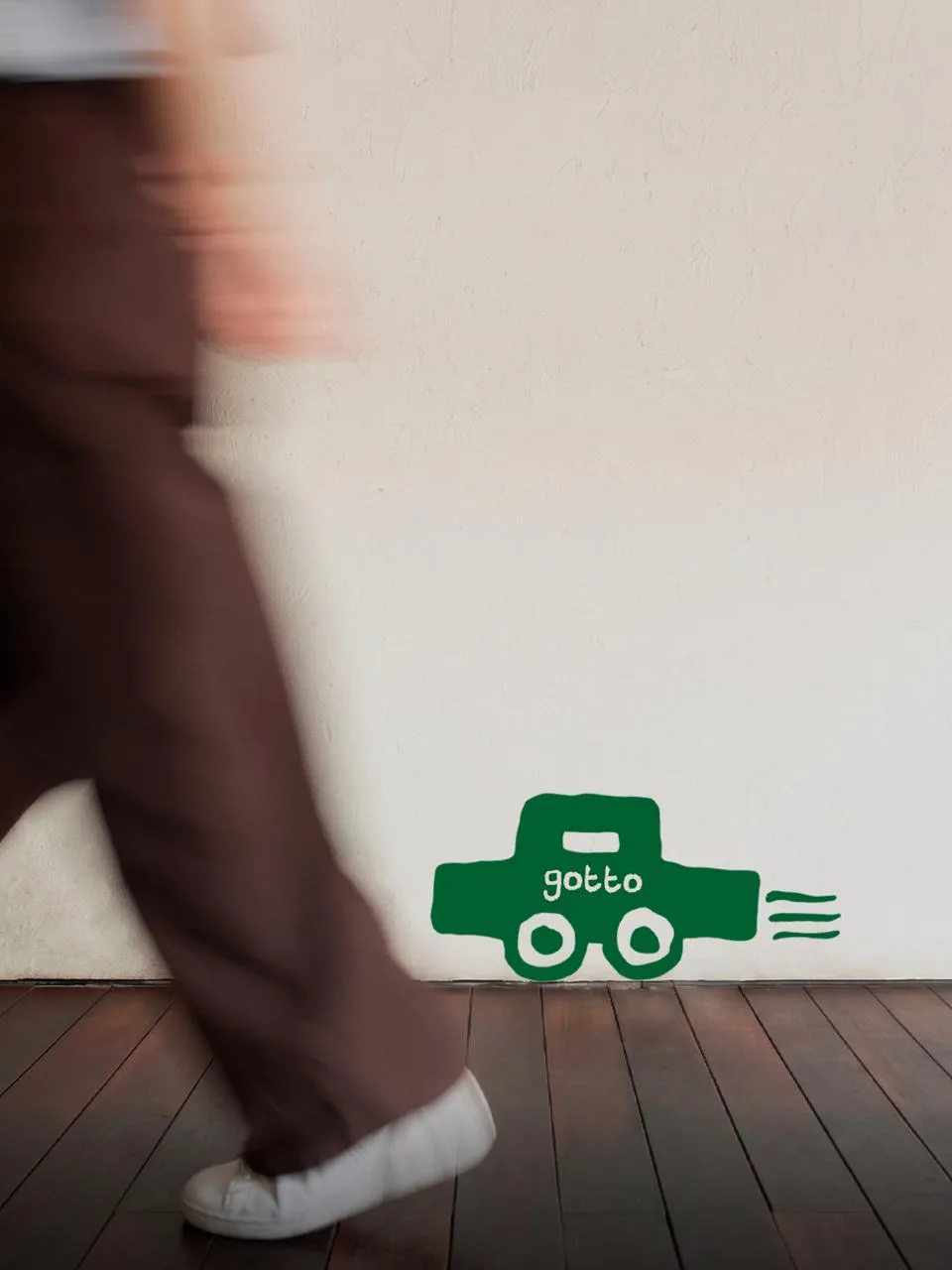 GOTTO: the toy car mark painted on a cafe wall as someone walks past