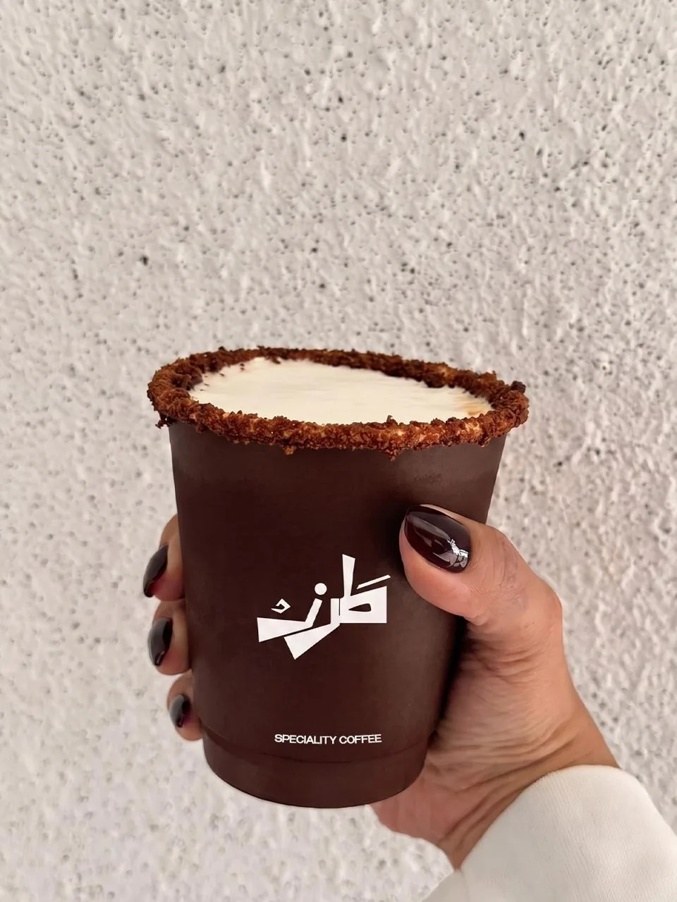 TRZ: the takeaway cup held against a plaster wall