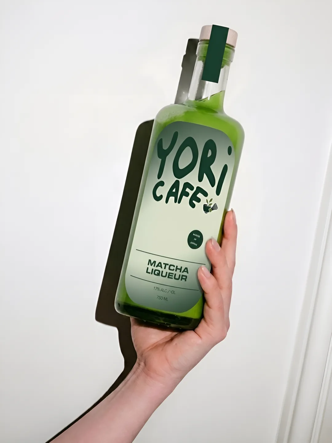 YORI CAFE: a hand holding a bottle of YORI CAFE matcha liqueur
